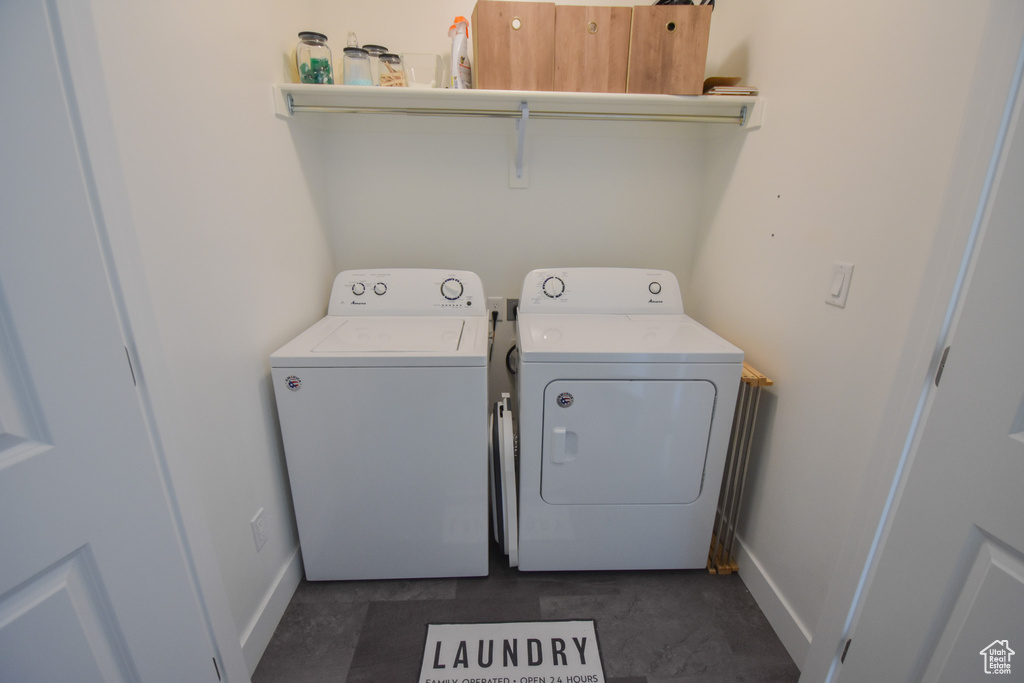 Clothes washing area with dark tile floors and washing machine and clothes dryer