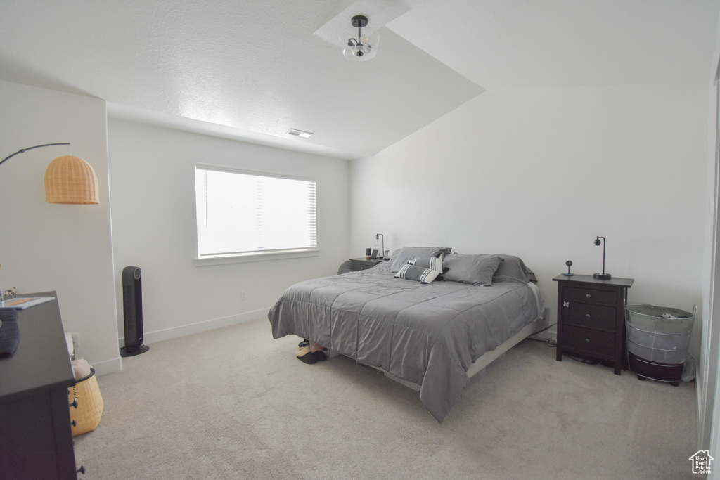 Bedroom featuring lofted ceiling and light colored carpet