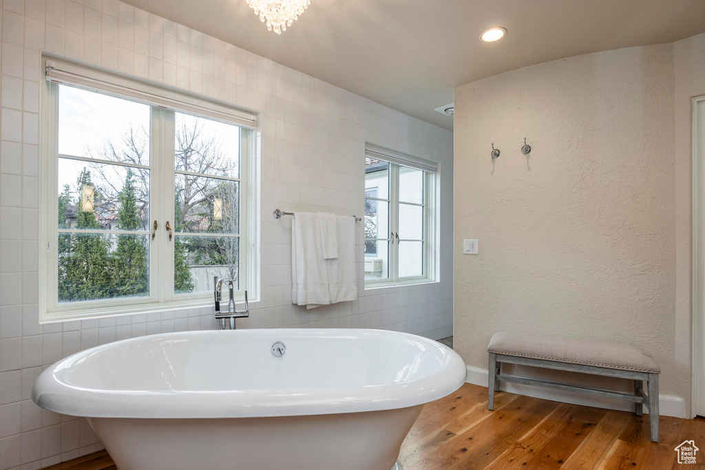 Bathroom featuring tile walls, hardwood / wood-style floors, and a washtub