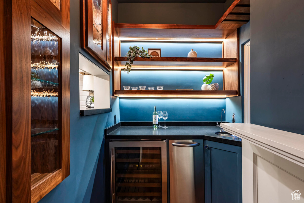 Bar featuring wine cooler, blue cabinets, and sink