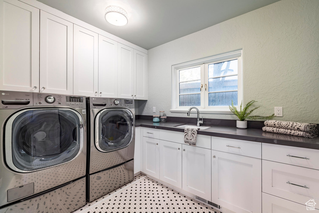 Laundry room with sink, light tile flooring, cabinets, and washer and clothes dryer