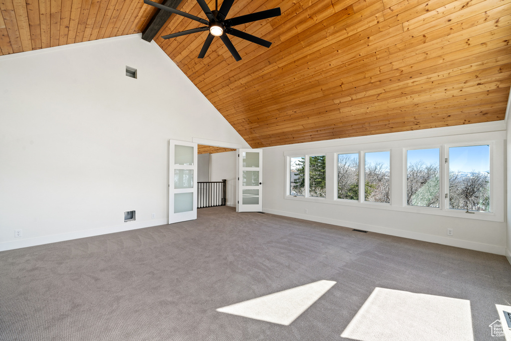 Interior space with ceiling fan, dark carpet, and wood ceiling