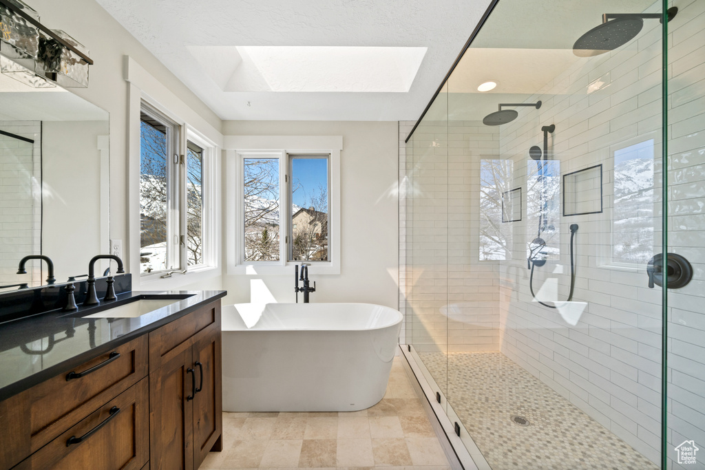 Bathroom with a skylight, oversized vanity, tile flooring, and plus walk in shower