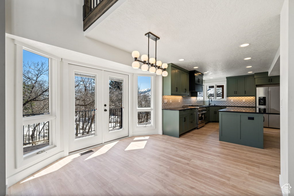 Kitchen with pendant lighting, french doors, backsplash, stainless steel appliances, and green cabinetry
