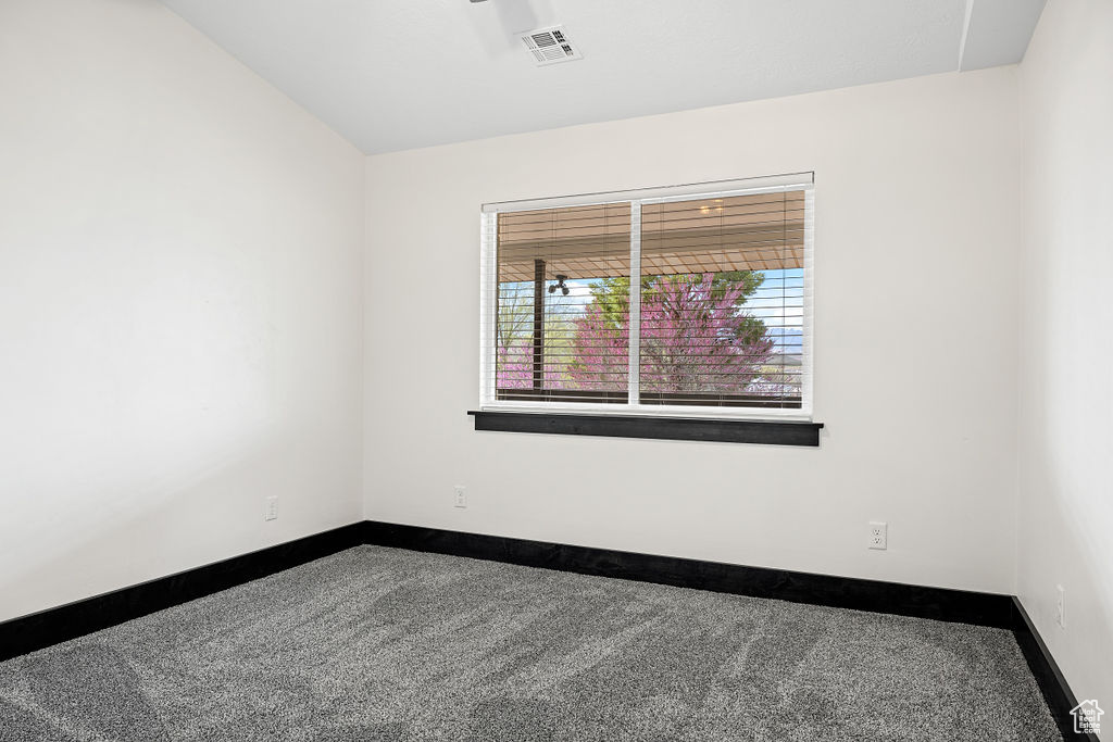 Carpeted spare room with lofted ceiling