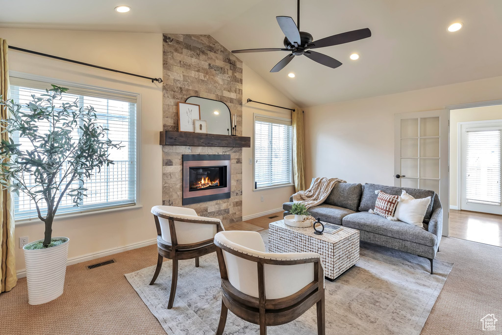 Living room with ceiling fan, light colored carpet, a fireplace, and vaulted ceiling