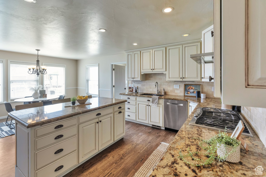 Kitchen featuring a notable chandelier, dark hardwood / wood-style floors, light stone countertops, tasteful backsplash, and dishwasher