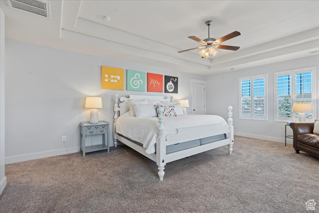 Bedroom featuring a raised ceiling, ceiling fan, and dark colored carpet