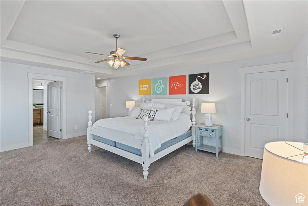 Bedroom featuring dark colored carpet, a tray ceiling, and ceiling fan