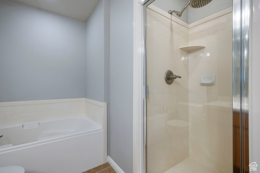 Bathroom featuring shower with separate bathtub, tile flooring, and toilet