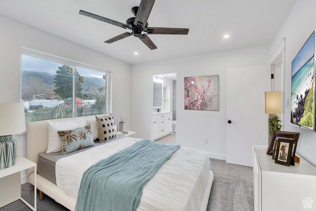 Bedroom with light carpet, ceiling fan, ensuite bathroom, and multiple windows