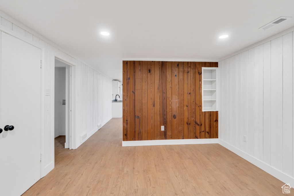 Basement featuring wood walls and light wood-type flooring