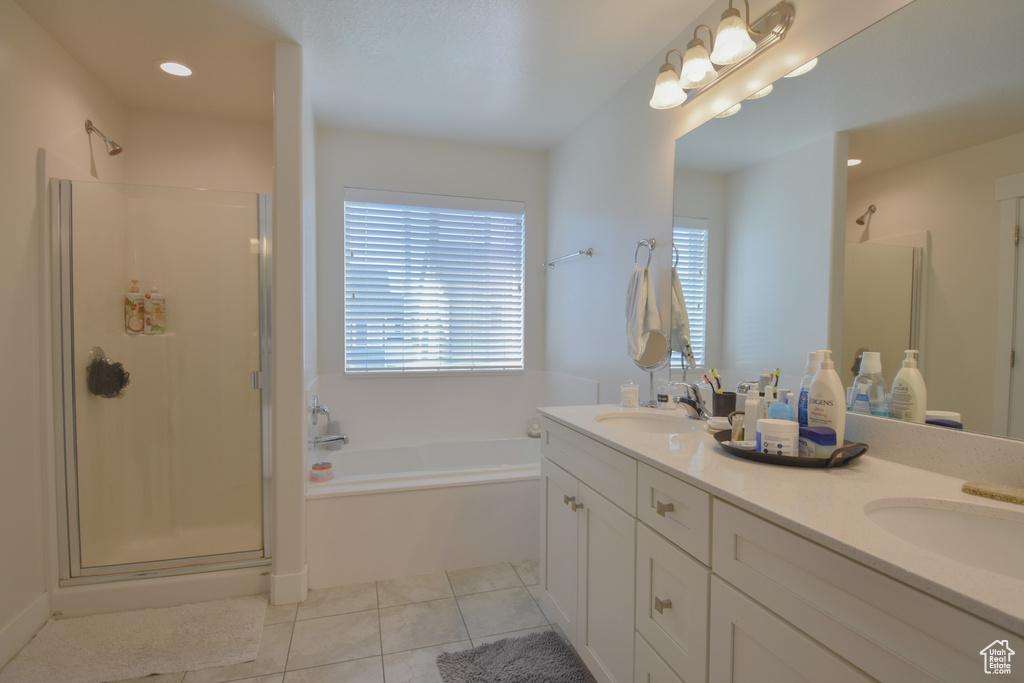 Bathroom featuring tile floors, plus walk in shower, oversized vanity, and dual sinks