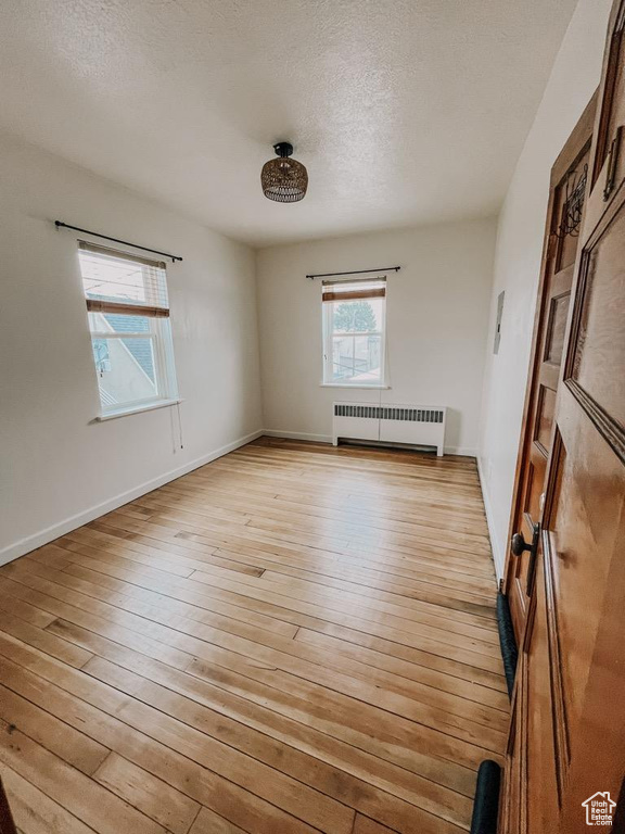Spare room featuring radiator, light hardwood / wood-style floors, and a textured ceiling