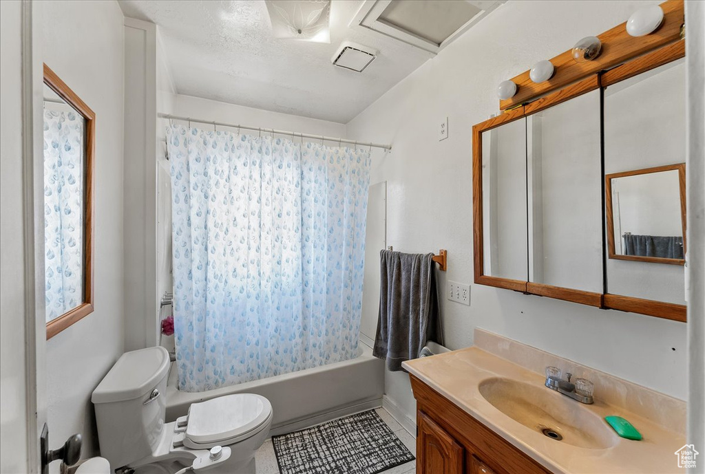 Full bathroom with tile flooring, shower / bath combination with curtain, toilet, and vanity