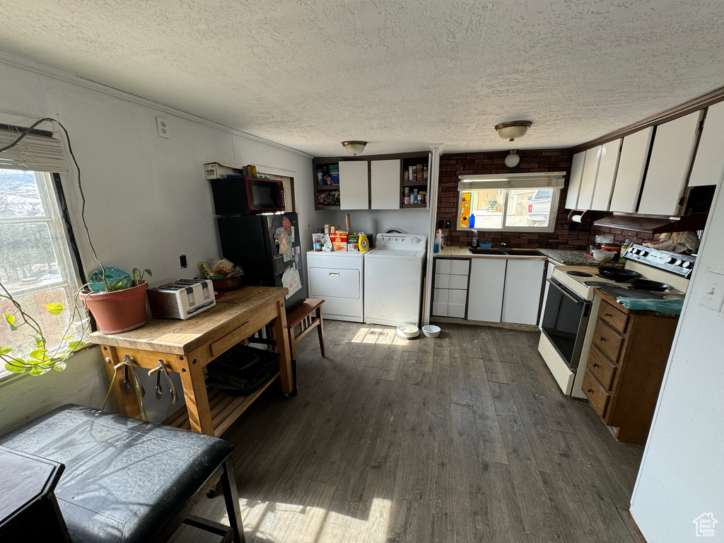 Kitchen with plenty of natural light, dark hardwood / wood-style floors, washing machine and clothes dryer, and white range with electric stovetop
