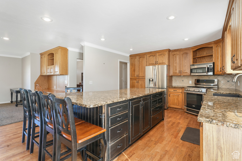 Kitchen with tasteful backsplash, light wood-type flooring, sink, and stainless steel appliances