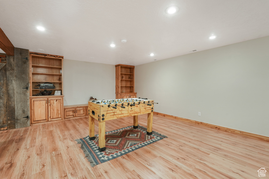 Game room with light hardwood / wood-style floors and built in shelves