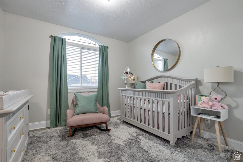 Bedroom featuring a nursery area and a textured ceiling