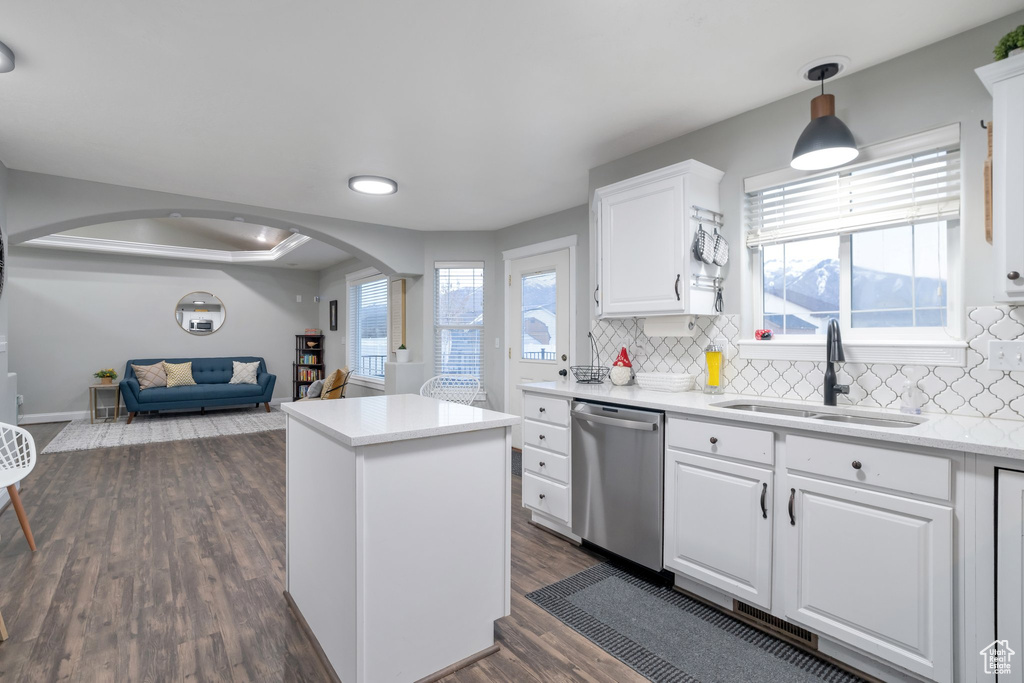 Kitchen featuring dark hardwood / wood-style floors, pendant lighting, sink, dishwasher, and white cabinetry