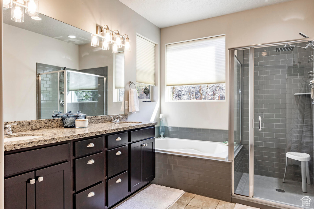 Bathroom featuring double sink, large vanity, tile floors, and plenty of natural light