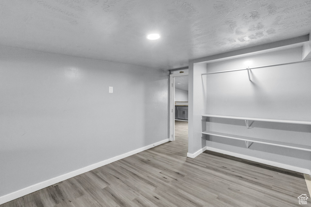 Basement with a textured ceiling and hardwood / wood-style flooring