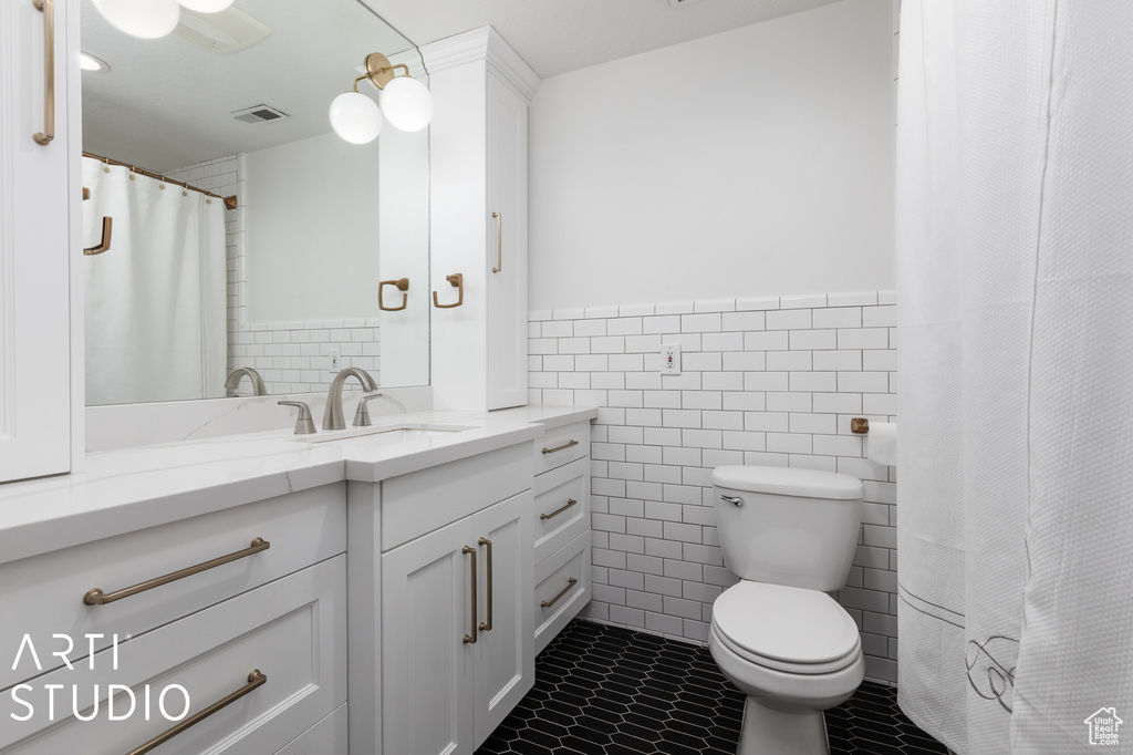 Bathroom featuring vanity, tile flooring, toilet, and tile walls