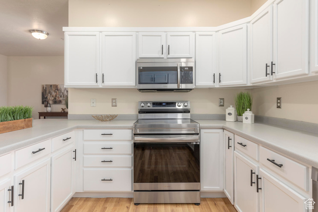 Kitchen featuring white cabinets, appliances with stainless steel finishes, and light wood-type flooring