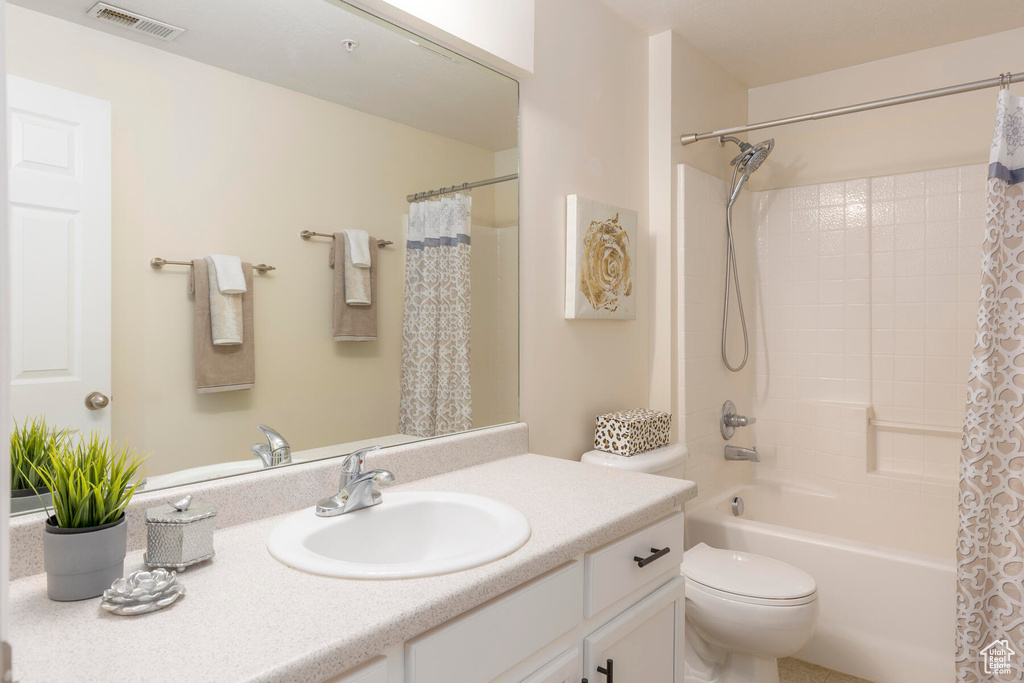 Full bathroom with oversized vanity, toilet, and shower / bath combo with shower curtain