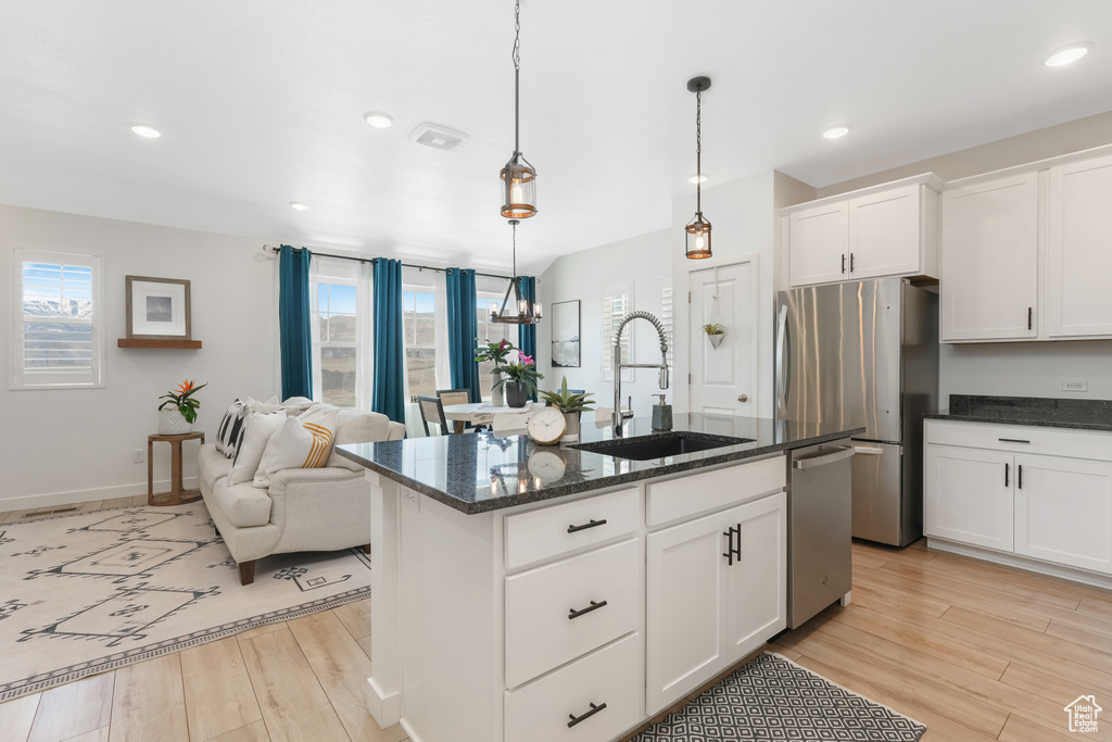 Kitchen featuring a chandelier, a center island with sink, light hardwood / wood-style flooring, hanging light fixtures, and sink