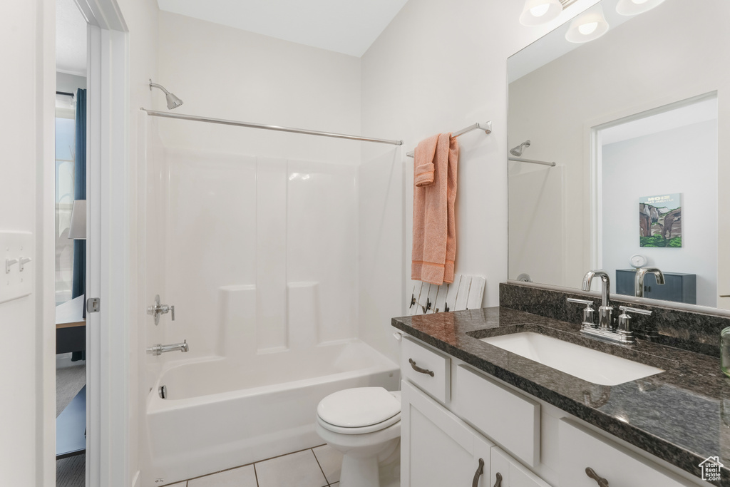 Full bathroom with tile floors, toilet, large vanity, and shower / tub combination