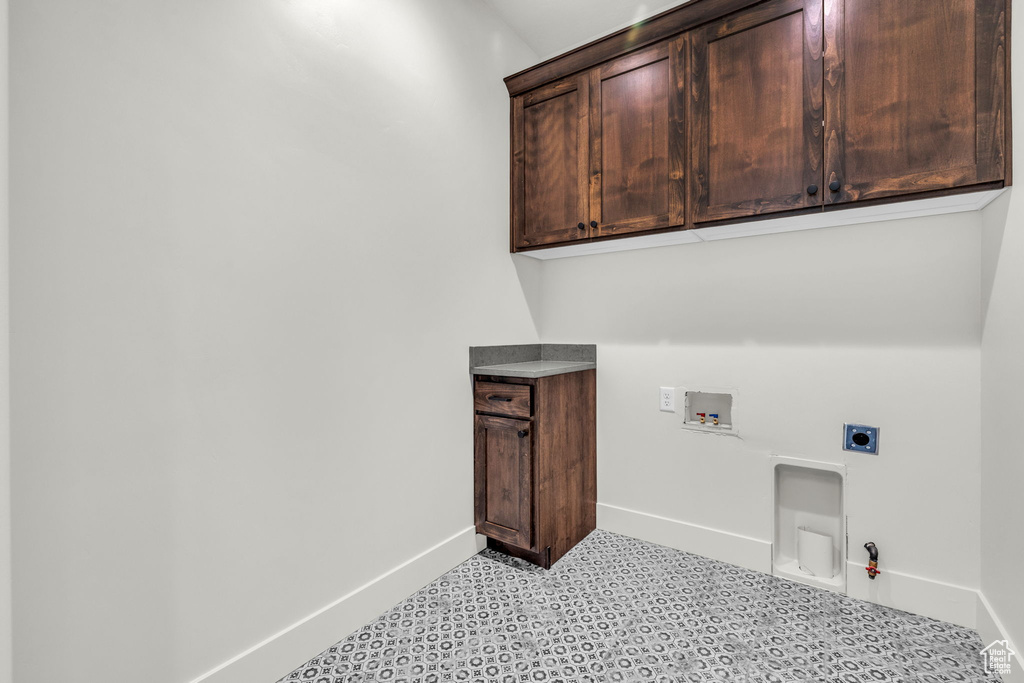 Washroom featuring light tile flooring, hookup for a gas dryer, cabinets, hookup for an electric dryer, and hookup for a washing machine