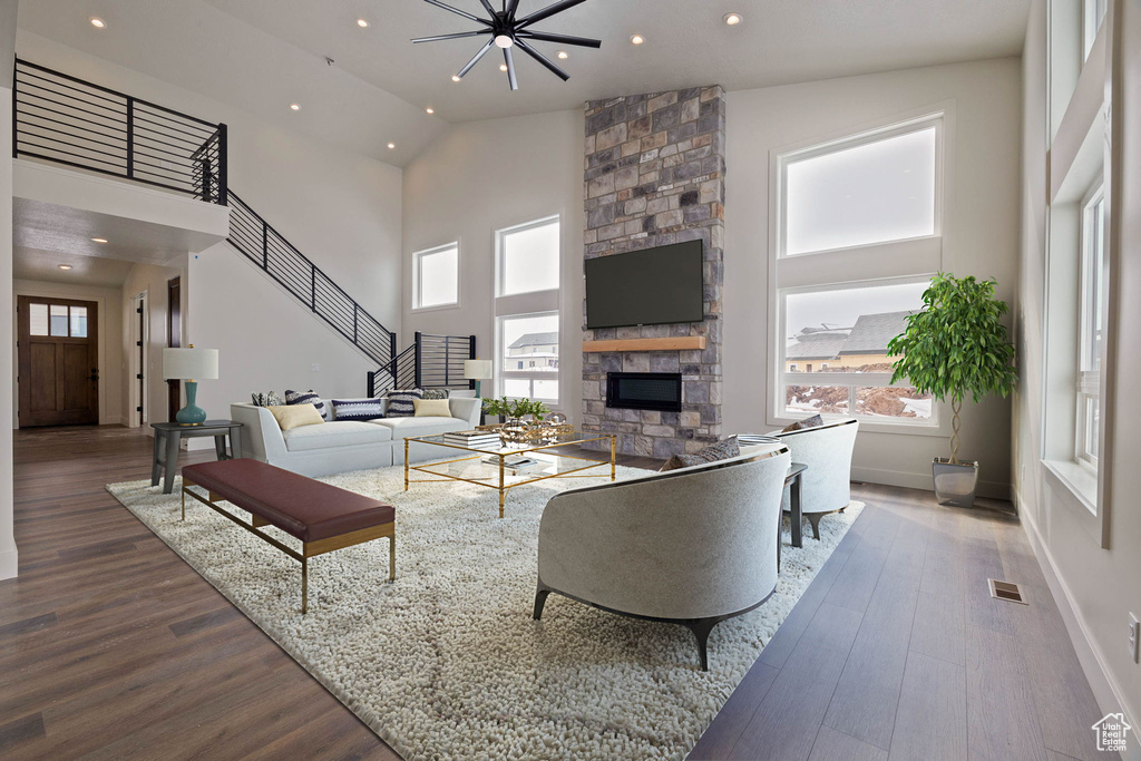 Living room featuring a fireplace, a wealth of natural light, high vaulted ceiling, and wood-type flooring