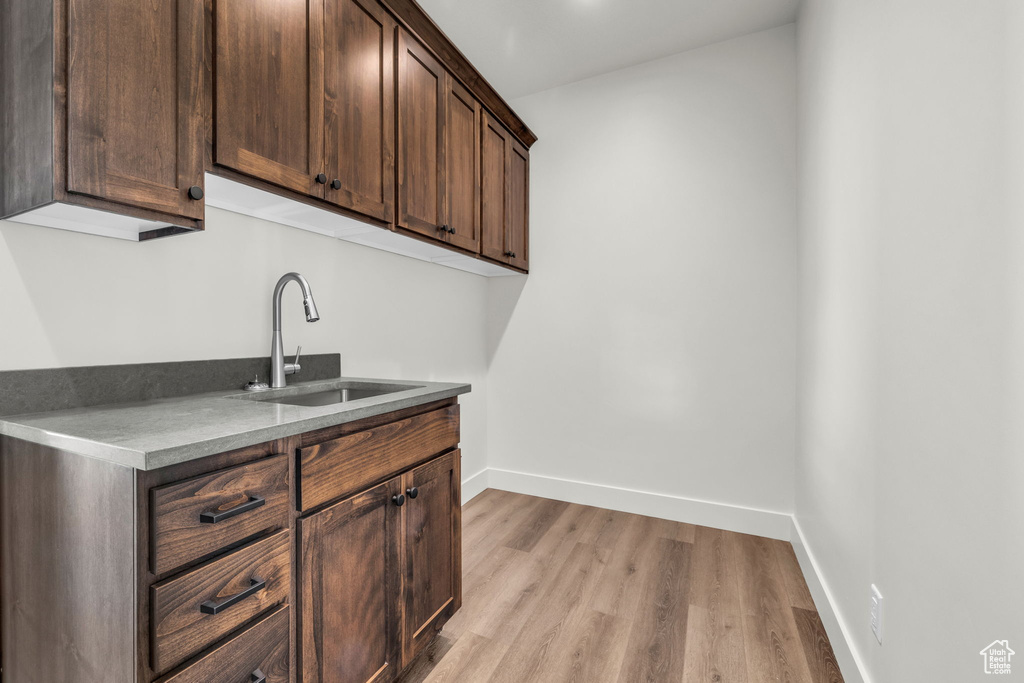 Kitchen featuring dark brown cabinets, sink, and light wood-type flooring