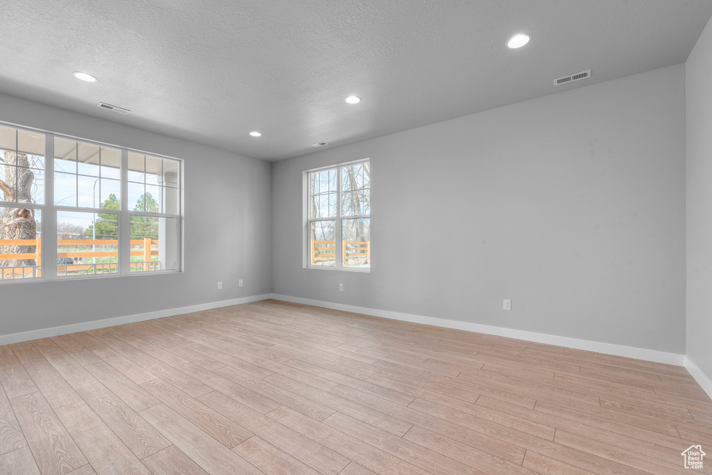 Empty room with light hardwood / wood-style floors and a textured ceiling