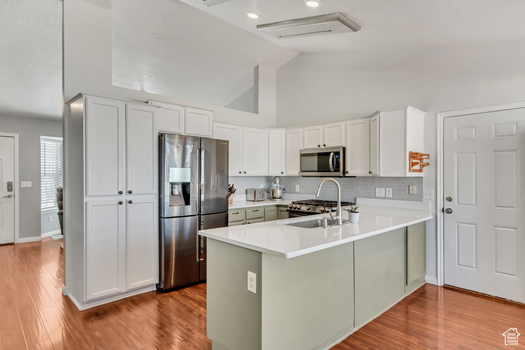 Kitchen featuring light wood-type flooring, stainless steel appliances, high vaulted ceiling, and kitchen peninsula