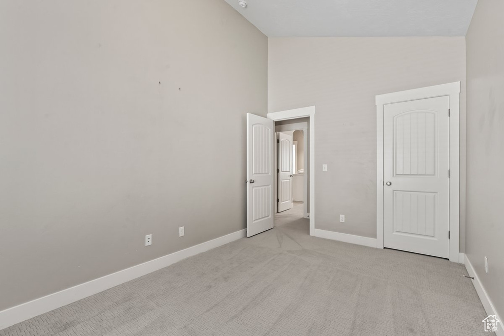 Unfurnished bedroom with lofted ceiling and light colored carpet