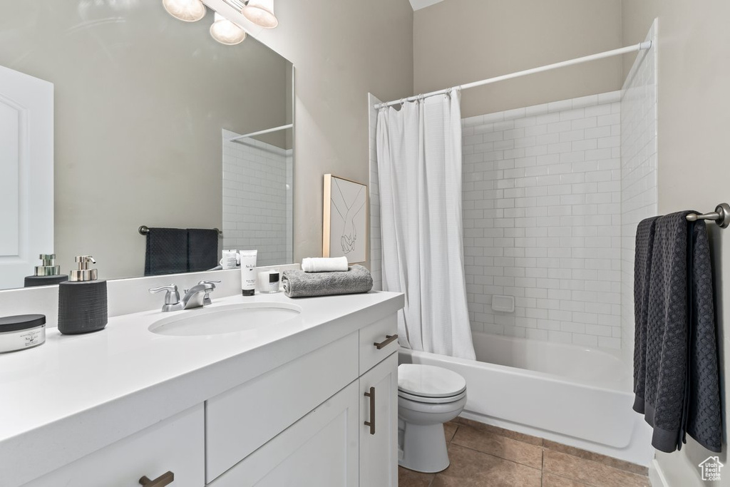 Full bathroom featuring shower / bath combination with curtain, toilet, vanity, and tile flooring