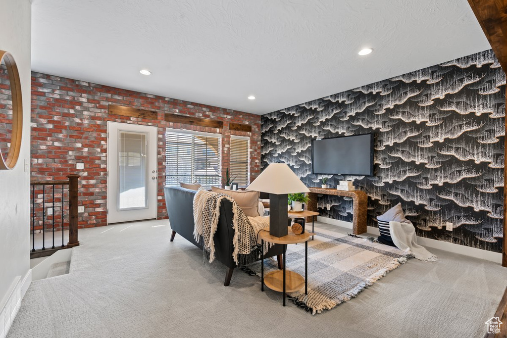 Carpeted living room with brick wall
