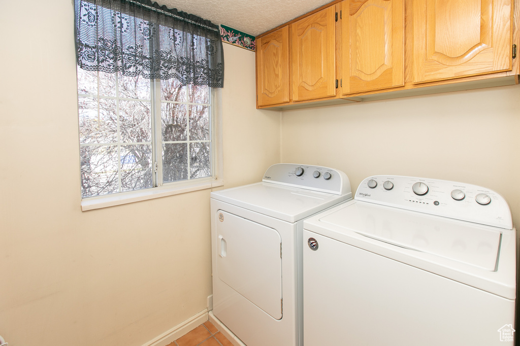 Washroom featuring separate washer and dryer, cabinets, and light tile floors