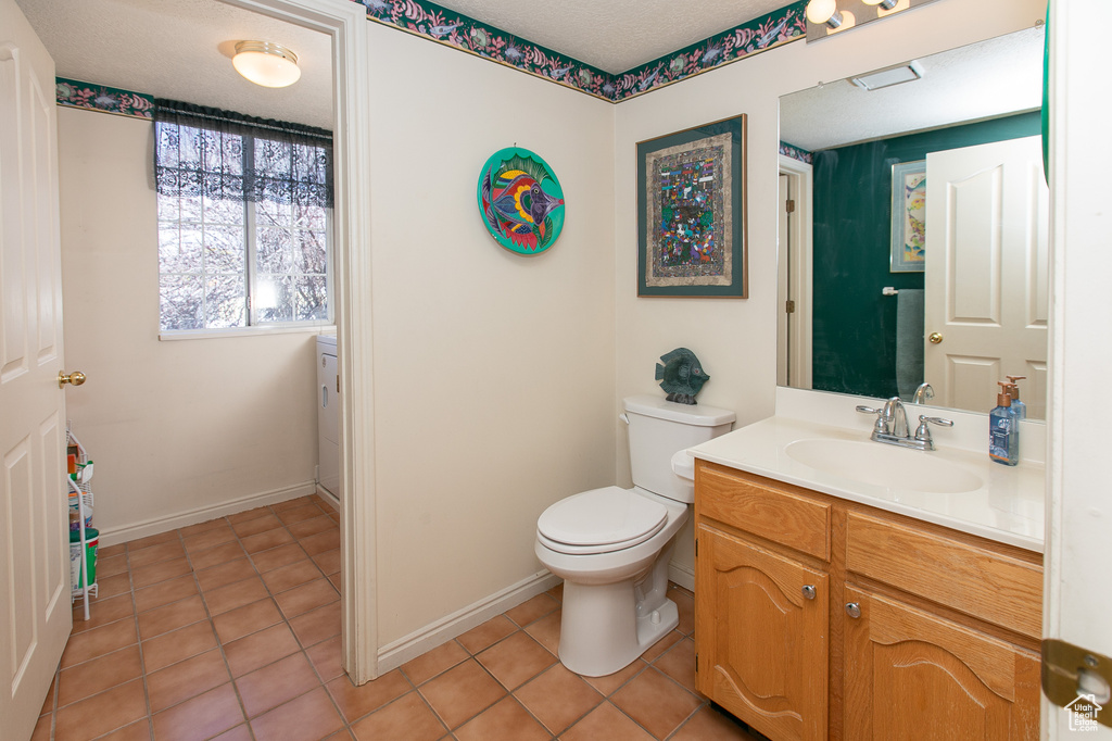 Bathroom featuring toilet, tile floors, a textured ceiling, and vanity