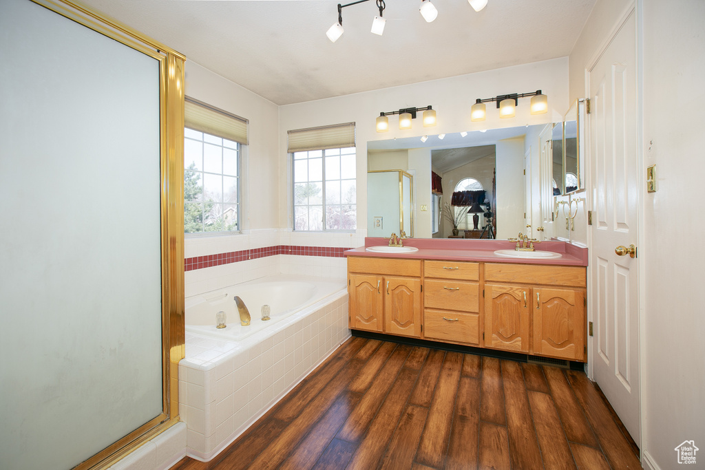 Bathroom with dual sinks, separate shower and tub, large vanity, and hardwood / wood-style floors