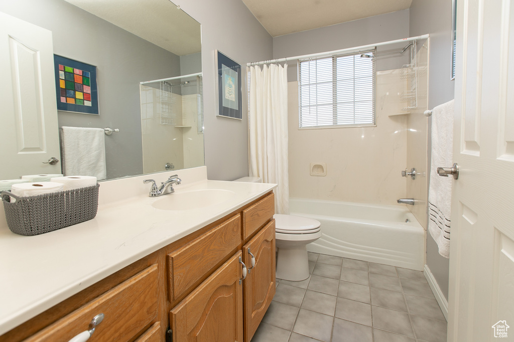 Full bathroom featuring tile floors, toilet, vanity, and shower / bath combo with shower curtain