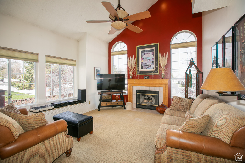 Carpeted living room featuring a fireplace, ceiling fan, and a towering ceiling