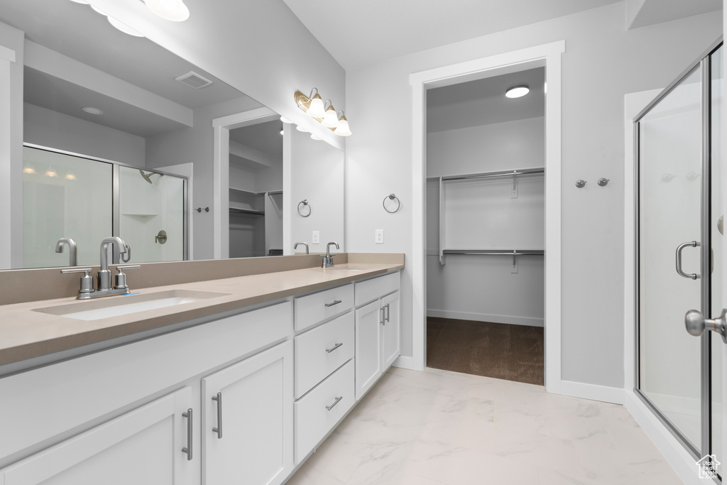 Bathroom featuring tile flooring, a shower with shower door, double sink, and oversized vanity