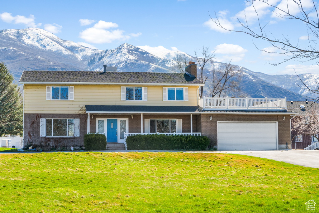View of property with a front lawn, a mountain view, and a garage