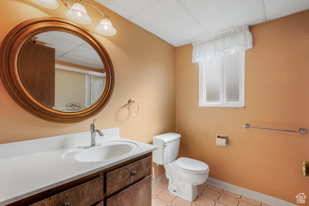 Bathroom with a paneled ceiling, vanity, tile flooring, and toilet