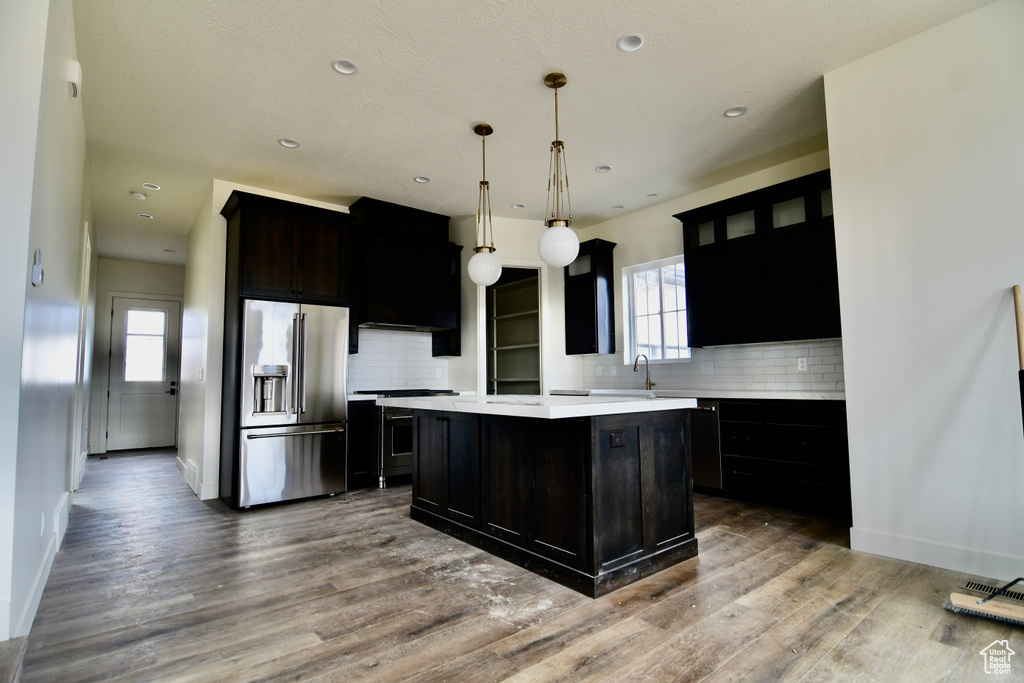 Kitchen with high end fridge, backsplash, a center island, and wood-type flooring