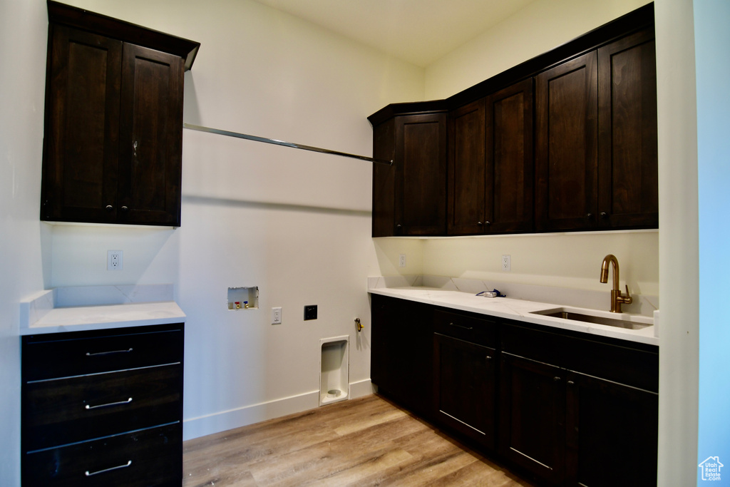 Laundry room with hookup for a gas dryer, light hardwood / wood-style floors, sink, cabinets, and washer hookup