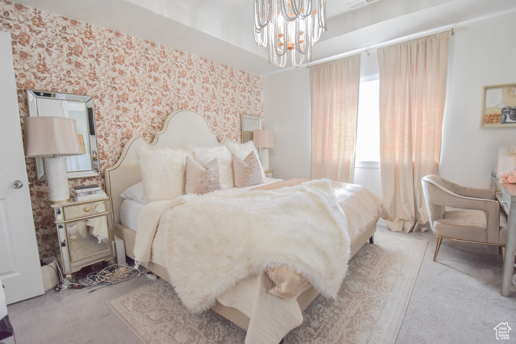 Bedroom with an inviting chandelier and light colored carpet
